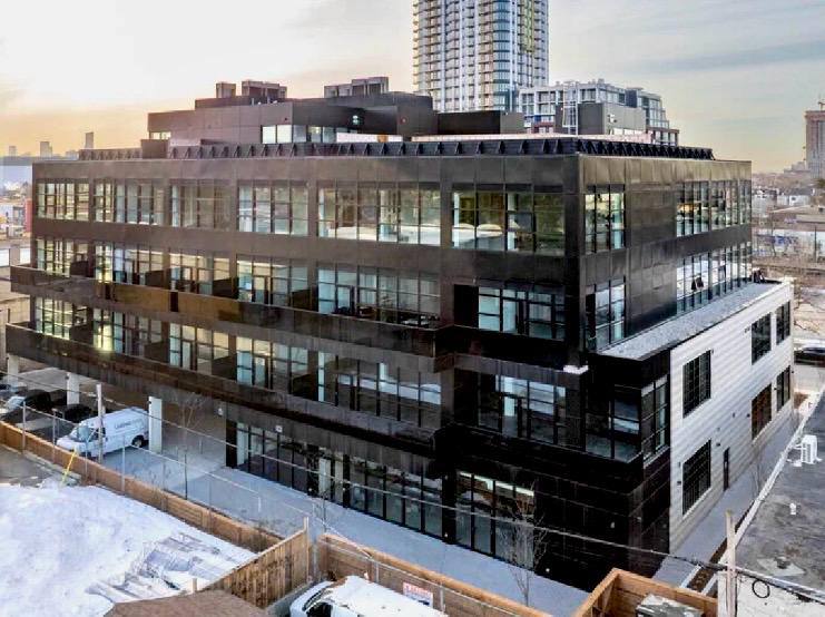 Dusk view of the modern glass-and-brick exterior with city skyline