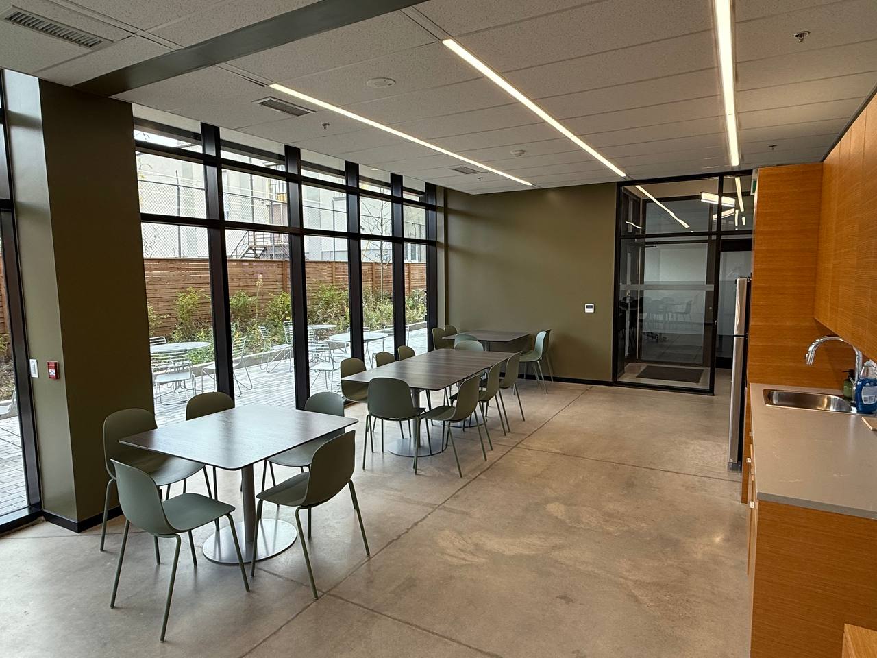 Members break lounge with dining tables, kitchenette, and outdoor patio access