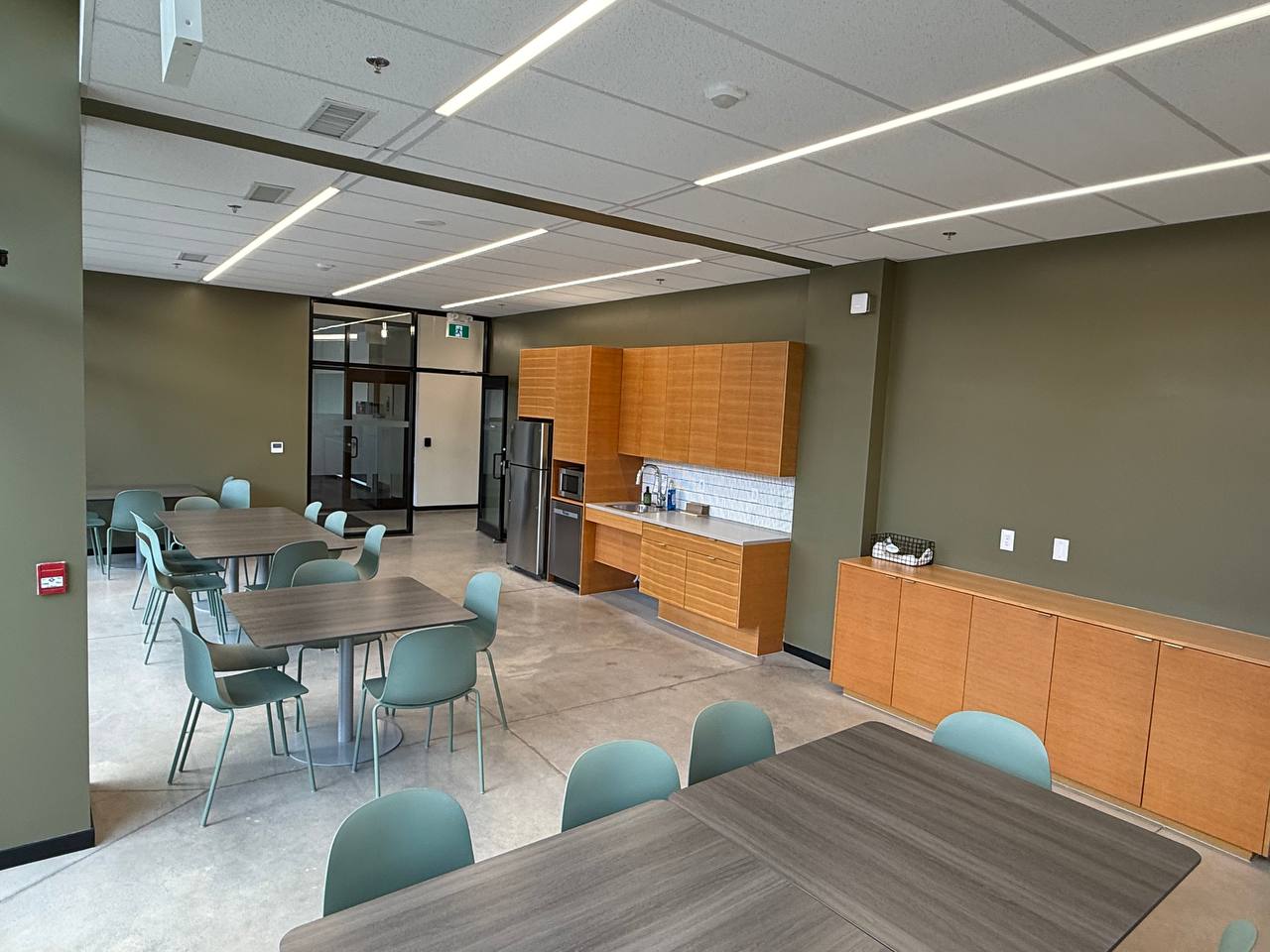 Community lounge with kitchenette, dining tables, and seating for breaks and meetings